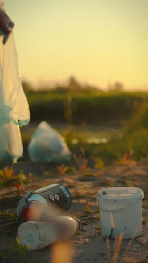 Man collects trash during sunset in a natural area to protect the environmen Stock Footage 331642576