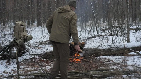 A man collects tree branches to build a shelter for warmth and protection from Video stock 324578882