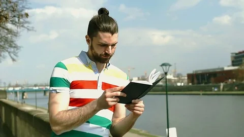 Man in colorful shirt having painful headache while reading book on boulevards Stock Footage