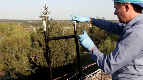 A man colors iron structure with black paint from a container Stock Footage 92441062
