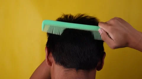 Man combing his hair isolated yellow background Stock Footage 275886053