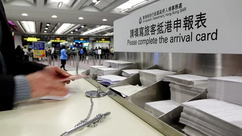Man come to fill arrival card, desk against document control area in HKG Stock Footage 327172297