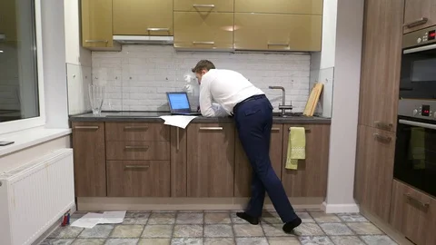 Man come at kitchen and bend to notebook computer standing at tabletop Video stock 72138739