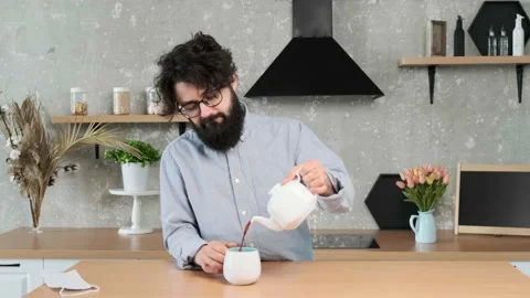 Man come in the kitchen, put off his medical mask, and pour himself a cup of tea Stock Footage 155807982