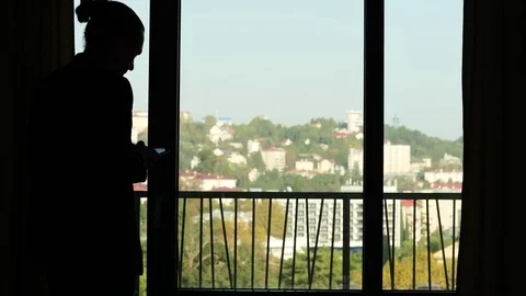 Man come to window while type messages on smartphone, black silhouetted view Stock Footage