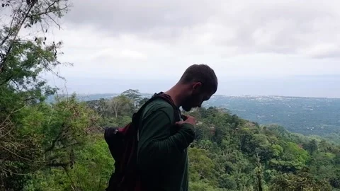 The man comes to a beautiful view and pulls something out of his backpack. Video stock 158817596