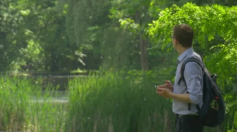 Man Comes Looking Around Texting on Smartphone Summer Forest Holding a Mobile Stock Footage 63809033