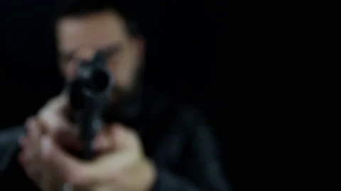 A man comes out of the dark walking with a gun in his hand Stock Footage 143486941