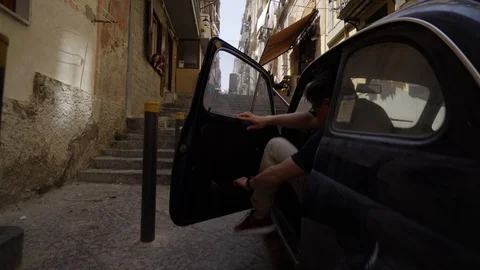 A man comes out of an old beetle and walks towards the Spanish quarters. Stock Footage 91853697