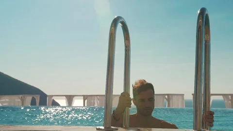 Man comes out of the pool on the stairs Stock Footage 145083944