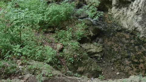 Man that comes from the river and sits on a rock taking into backpack in hand Stock Footage 78220762