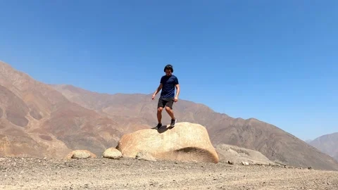 A man coming down from a big rock to continue running after resting in strong wi Stock Footage 199551306