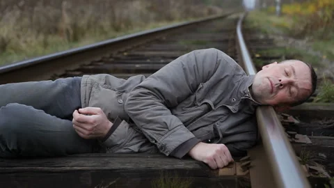 Man commits suicide.Man lies down on the railroad and rests his head on rails Stock Footage 143235074