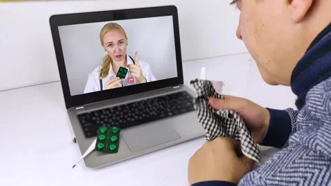 A man communicates via a computer with a doctor via video link. Medical assistan Stock Footage 140264353