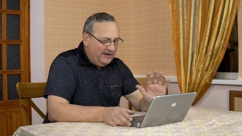 A man communicates with friends via video calling through a laptop. An old man Stock Footage 124711383