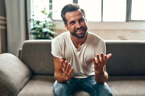 A man communicates on a video call while sitting on the couch in the living r Stock Photos