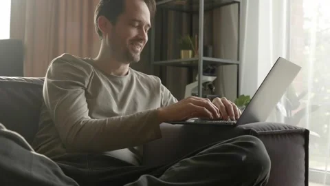 A man communicates via video link using a laptop while at home on the couch Stock Footage 253403222