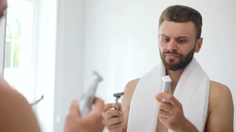 Man compares two trimmers Stock Footage 142225356