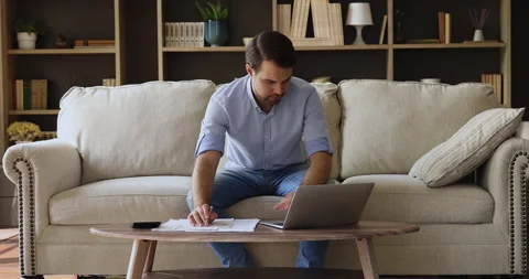 Man comparing data, check receipts and invoices working from home Stock Footage 168969951