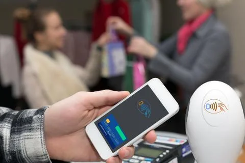 Man completing mobile Payment at Store Cashiers Desk with Terminal Stock Photos