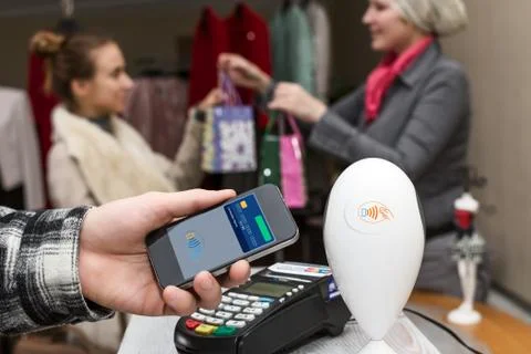 Man completing mobile Payment at Store Cashiers Desk with Terminal Stock Photos