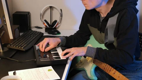 Man composing on MIDI keys with guitar in studio Stock Footage 295877958