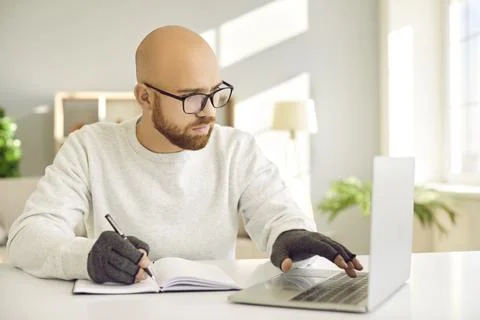 Man in compression gloves for relieving arthritis pain using computer and Foto stock