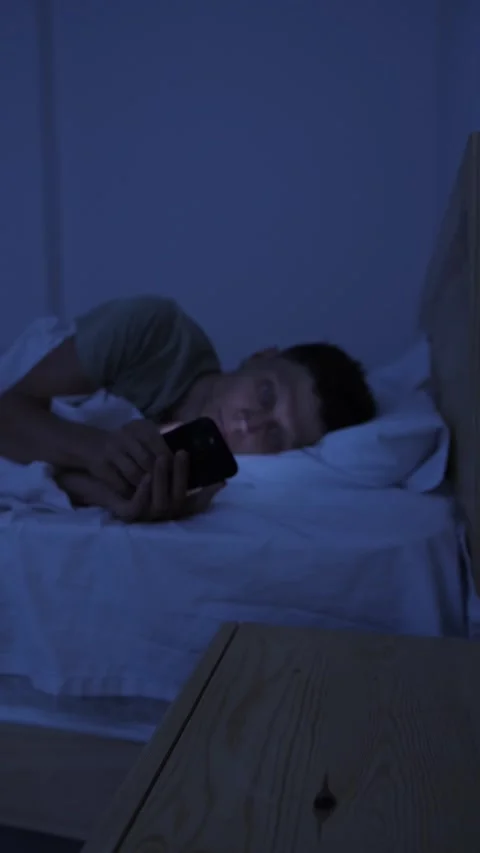 Man compulsively scrolling smartphone in bed at night, struggling with digital 스톡 동영상 346245908