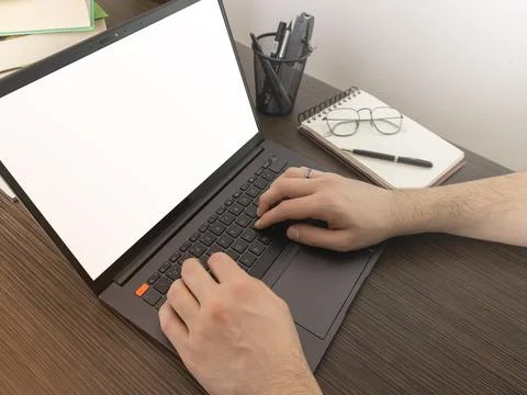 A man at a computer. Close-up of a hand, Mockup. White laptop and phone screen. Stock Photos