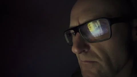 Man on a computer in Dark room, screen reflection in glasses. Hull.UK. 1.1.2026 Stock Footage 327158680