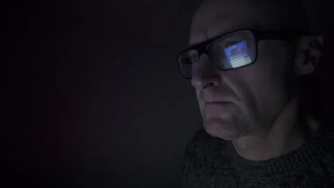 Man on computer in Dark room, screen reflection in glasses. Hull.UK. 1.3.2026 Stock Footage 327158717