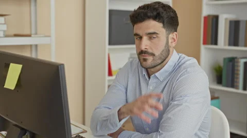 Man at computer with finger to lips performing shushing gesture in office b.. 库存影片 337373355