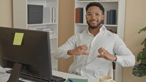 Man at computer forms heart with hands while smiling at camera in office we.. Stock Footage 337439886