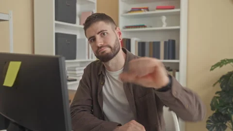 Man at computer gives thumbs down and types with one hand while seated in a.. Stock Footage 337362719