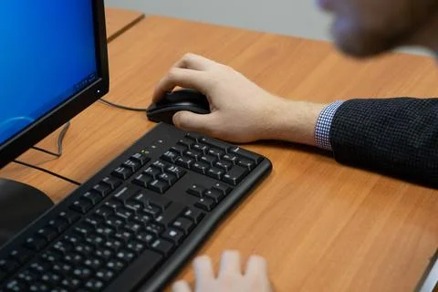 Man at the computer, hand on the mouse Stock Photos