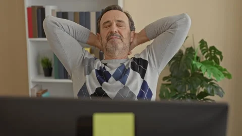 Man at computer leans back in chair with hands behind head, eyes closed and.. Video stock 337443526