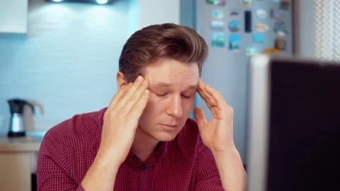 A man at a computer massages his head from fatigue Stock Footage 145134543