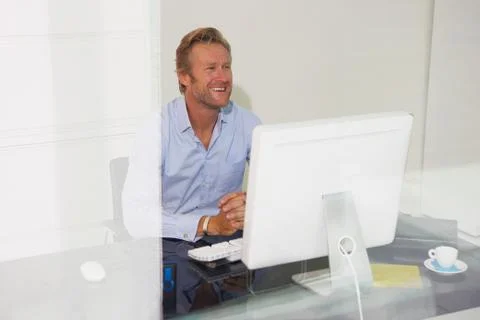 Man at computer smiling with reflections. Stockfoto's