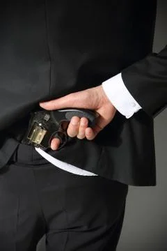 A man conceals a firearm in the back of his pants. Stock Photos
