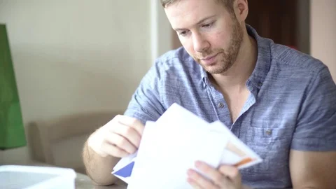 A Man is Concerned and Stressed Looking Through Debt Bill Letters Stock Footage 78620301