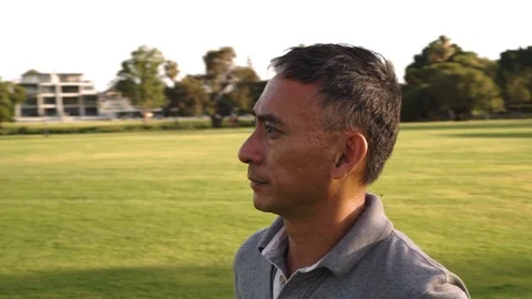 Man with concerned expression in park, dramatic rotating shot, slow motion Stock Footage 121874690