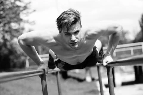 Man with confident face performs on parallel bars Stock Photos