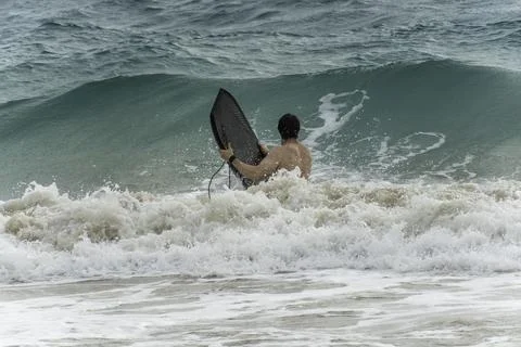A man is confidently holding a surfboard while out in the ocean Stock Photos