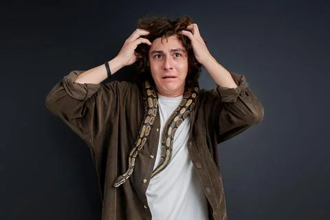 Man in confusion does not know what to do with snake on him, grabbed his head Stock Photos