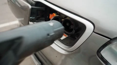 Man Connecting A Power Supply Cable Into An Electric Car For Charging An EV Видео 156790992