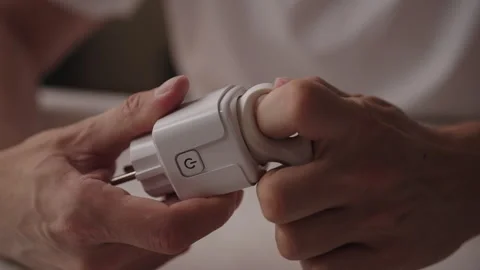 Man connecting smart plug to standard European plug, enabling remote control and Stock Footage 317302647