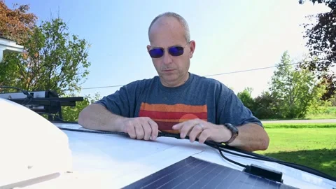 Man connecting solar panel connection cables on top of a camper Stock Footage 253097708