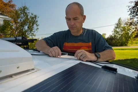 Man connecting solar panel connection cables on top of a recreational vehicle. Stock Photos