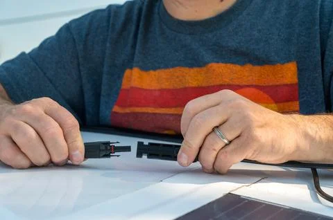 Man connecting solar panel connection cables on top of a recreational vehicle. Stock Photos