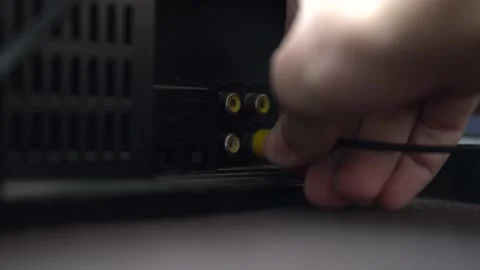 A man connects a AV cable to the VCR Video stock 234407543